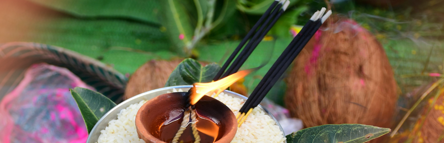Two incense sticks are burning, creating flames above the pot