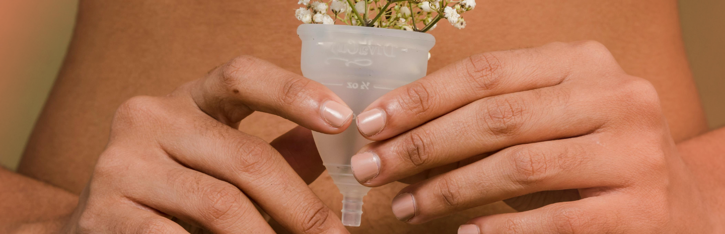 A person holding a menstrual cup with small white flowers inside, symbolizing menstruation in a gentle and natural way
