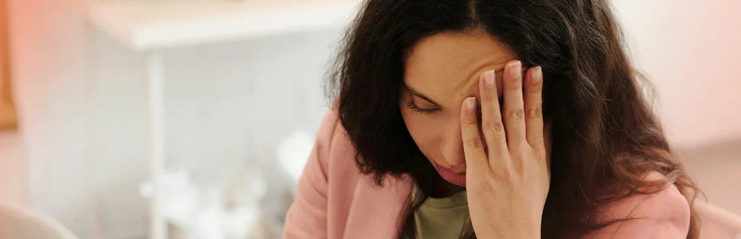The image shows a woman with her hand on her face, appearing stressed, tired, or overwhelmed.