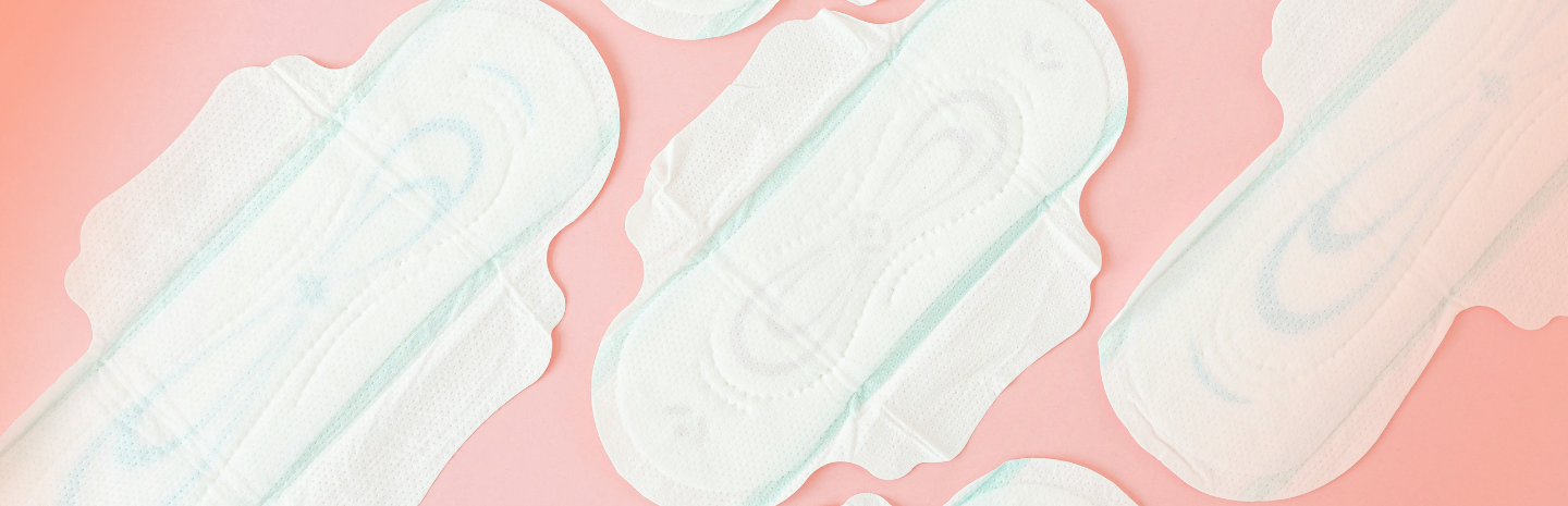 Several white panty liners are spread out on a soft pink surface, illustrating traditional options for daily leak protection