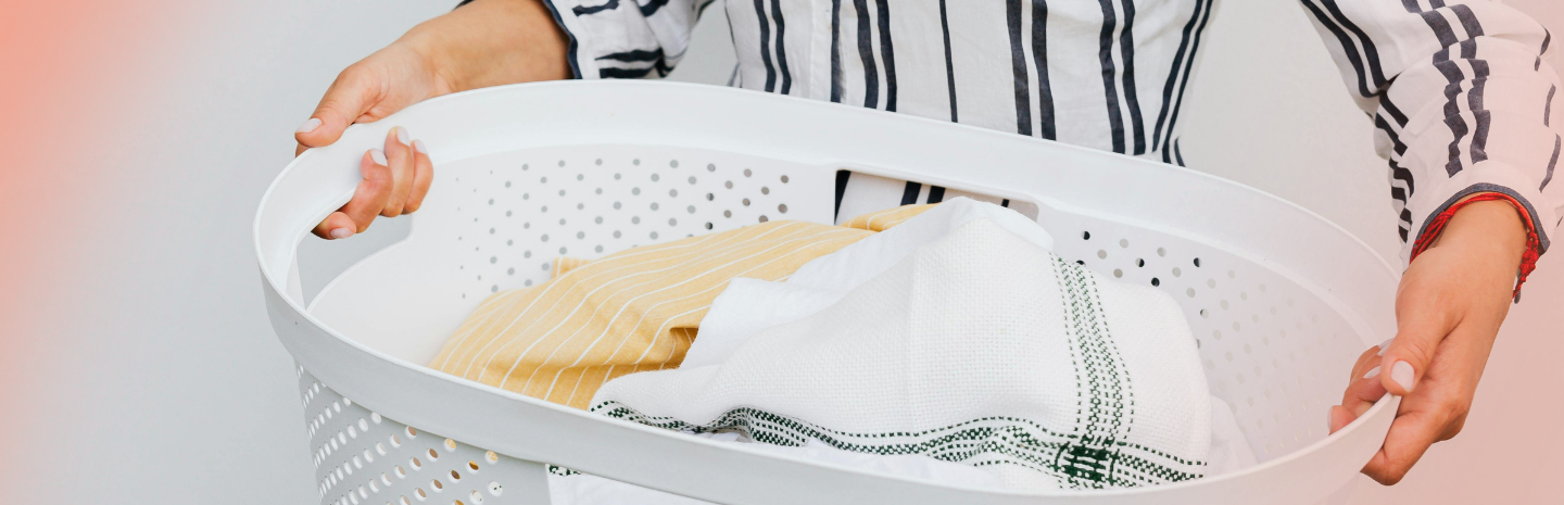 A person holds a laundry basket with freshly washed period panties and clothes, ready for drying.