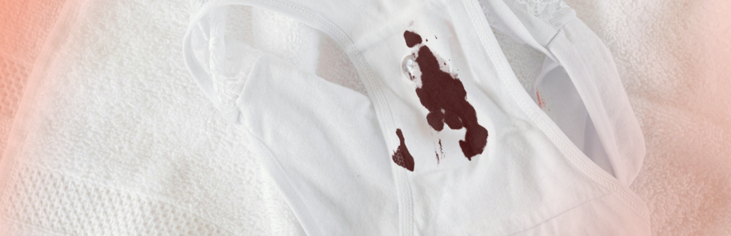 White period panty with a noticeable brown blood stain on the crotch area, lying on a white towel background