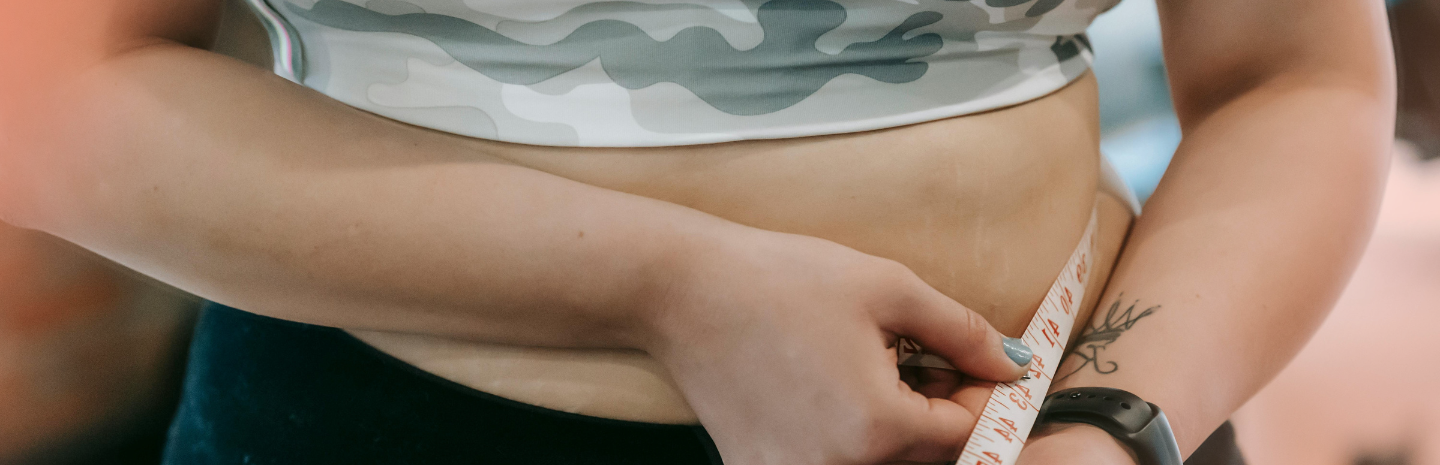 Woman measuring waistline, indicating signs of thyroid problems in women affecting weight and irregular periods.